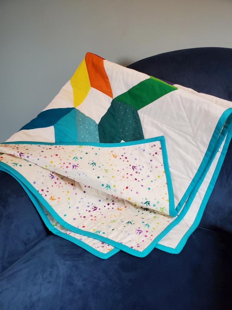 closeup of folded quilt on a blue chair showing the backing fabric